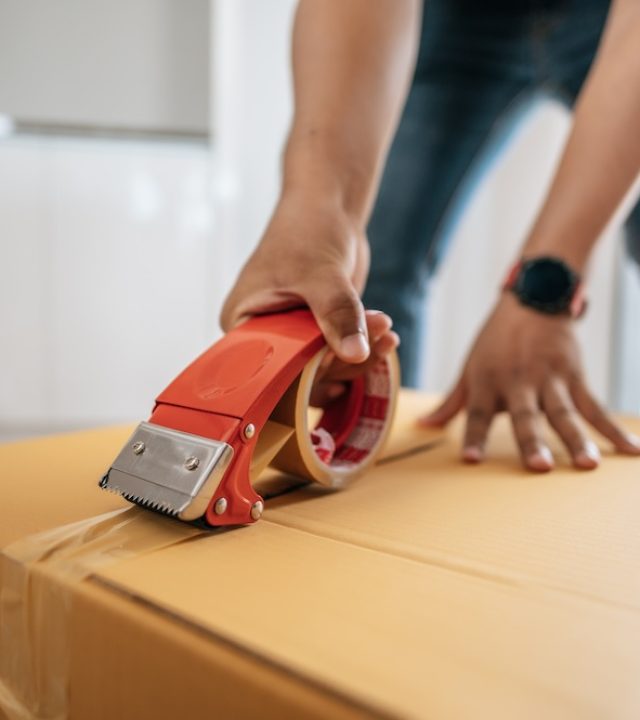 Close up hand of man use glue tape to close cardboard box, sealing big box for packing moving, new house concept, Selective focus	cardboard box,